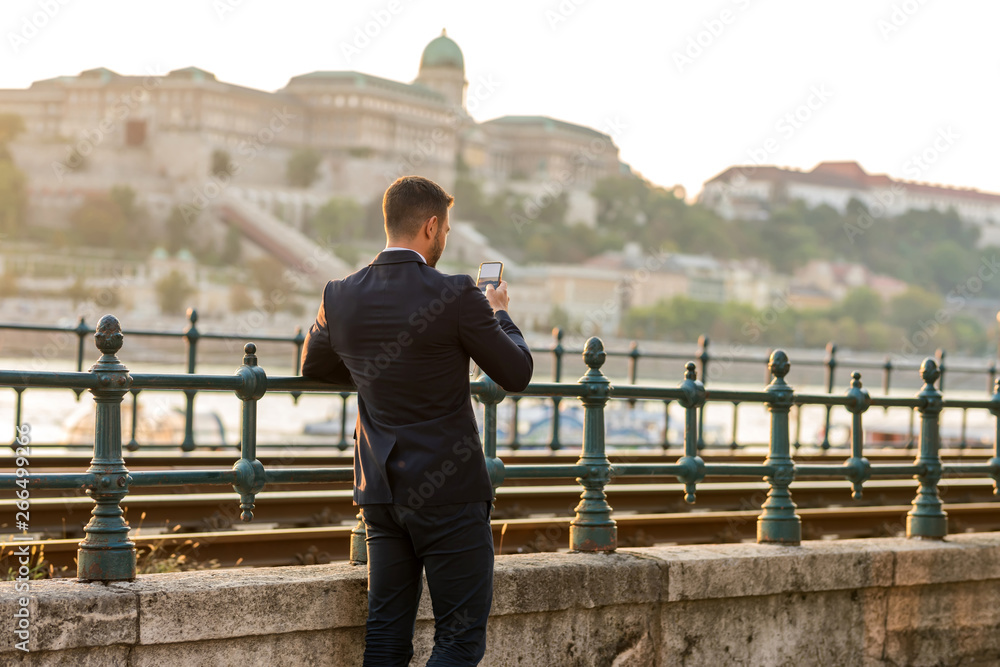 A businessman next to a tramline taking a photo A businessman next to a tramline taking a photo
