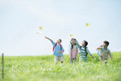 草原で紙飛行機を飛ばす小学生