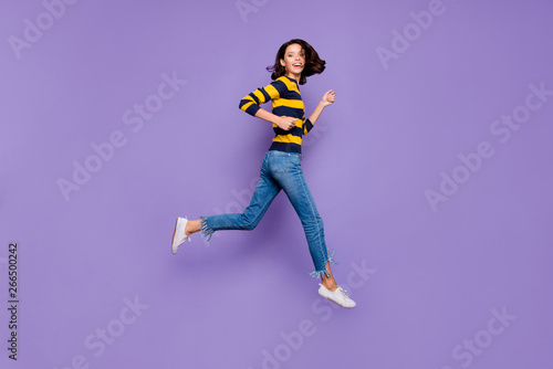 Full length side profile body size photo beautiful she her lady cheerful jump high flight hurry shopping sale discount mall store wear blue yellow striped pullover isolated violet purple background © deagreez