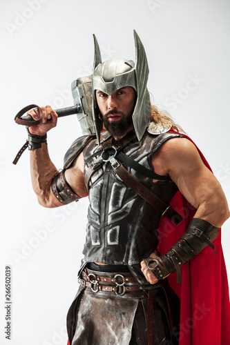 фотографія Long hair and muscular male model in leather viking's costume with the big hammer cosplaying Thor isolated on white studio background