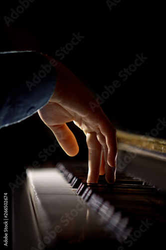 one male hand on the piano. The palm lies on the keys and plays the keyboard instrument in the music school. student learns to play. hands pianist. black dark background. vertical