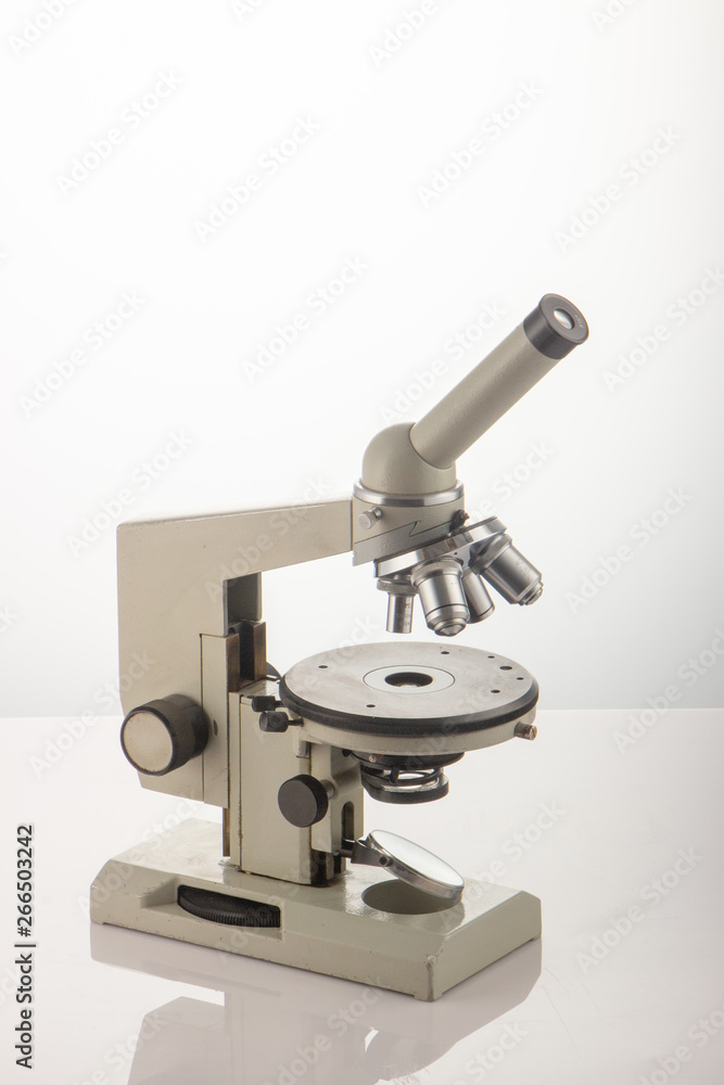 White microscope on table over white background close up White microscope on table over white background close up
