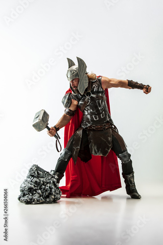 Canvas Print Long hair and muscular male model in leather viking's costume with the big hammer cosplaying Thor isolated on white studio background