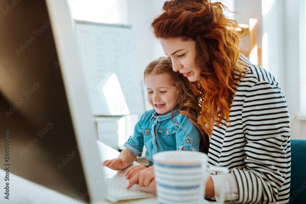 Daughter sitting on knees of mother and trying using keyboard Daughter sitting on knees of mother and trying using keyboard