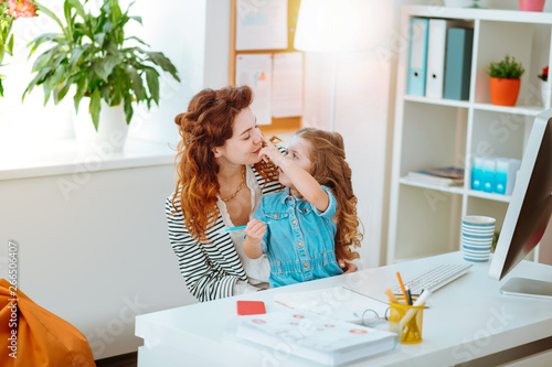 Cute girl touching nose of mother working remotely at home