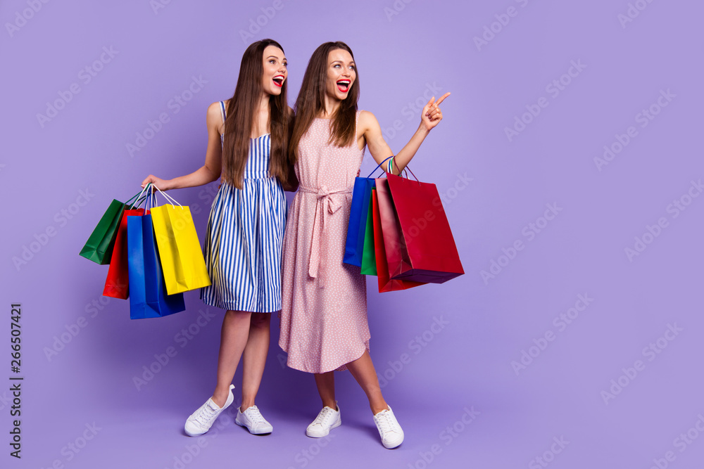 Full length body size photo two people beautiful she her models chic ladies carry many packs direct empty space laugh laughter fellowship wear casual dresses isolated purple violet bright background Full length body size photo two people beautiful she her models chic ladies carry many packs direct empty space laugh laughter fellowship wear casual dresses isolated purple violet bright background