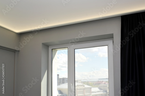 Window in the living room with the hidden LED illumination of a stretch ceiling