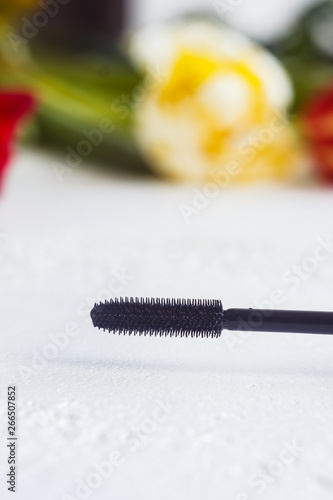 black mascara brush close up on white table. macro on blurred background. vertical