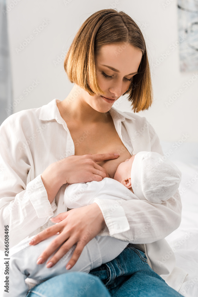 Young mother in white shirt breastfeeding baby at home Young mother in white shirt breastfeeding baby at home
