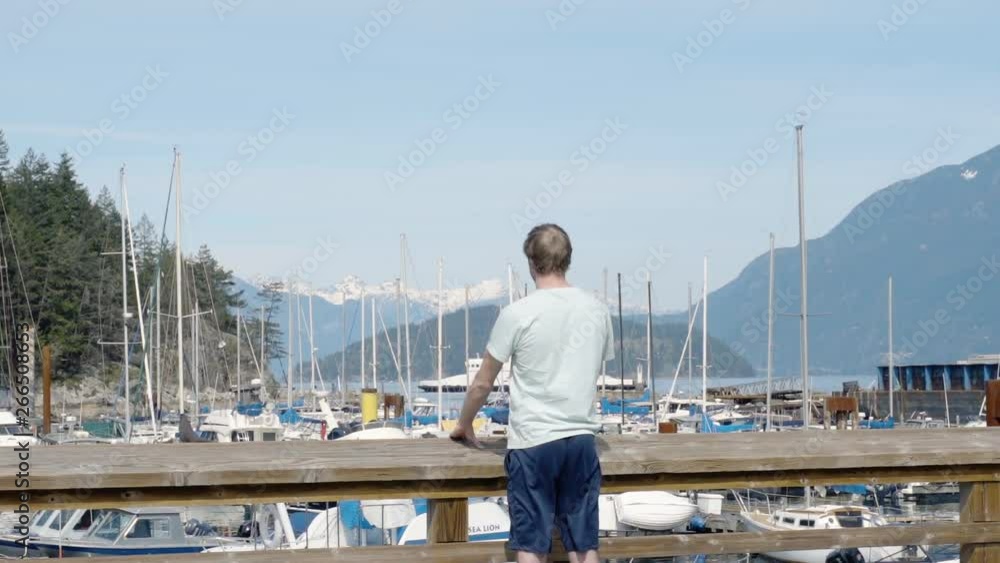 Slow Motion Man Standing At Wooden Railing On Wharf Over Ocean In Marina Slow Motion Man Standing At Wooden Railing On Wharf Over Ocean In Marina