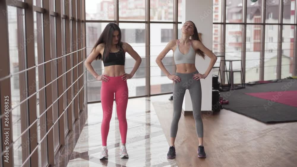 Two fit models warm up in the gym. Although they roll their necks in the wide circle, they still have fun, laugh and keep a pleasant conversation. Two fit models warm up in the gym. Although they roll their necks in the wide circle, they still have fun, laugh and keep a pleasant conversation.