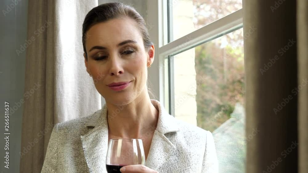 Close up attractive, classy white caucasian woman holding glass of wine looking out window. Left pan, slow motion. Close up attractive, classy white caucasian woman holding glass of wine looking out window. Left pan, slow motion.
