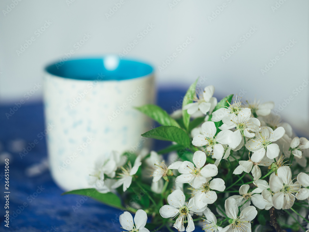 Spring tea with petals of cherry blossoms on a blue background Spring tea with petals of cherry blossoms on a blue background