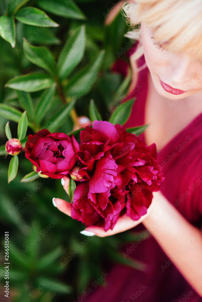 Outdoor close up portrait of beautiful young woman with long blonde hair, makeup, posing in the blooming garden. Female spring fashion concept Outdoor close up portrait of beautiful young woman with long blonde hair, makeup, posing in the blooming garden. Female spring fashion concept
