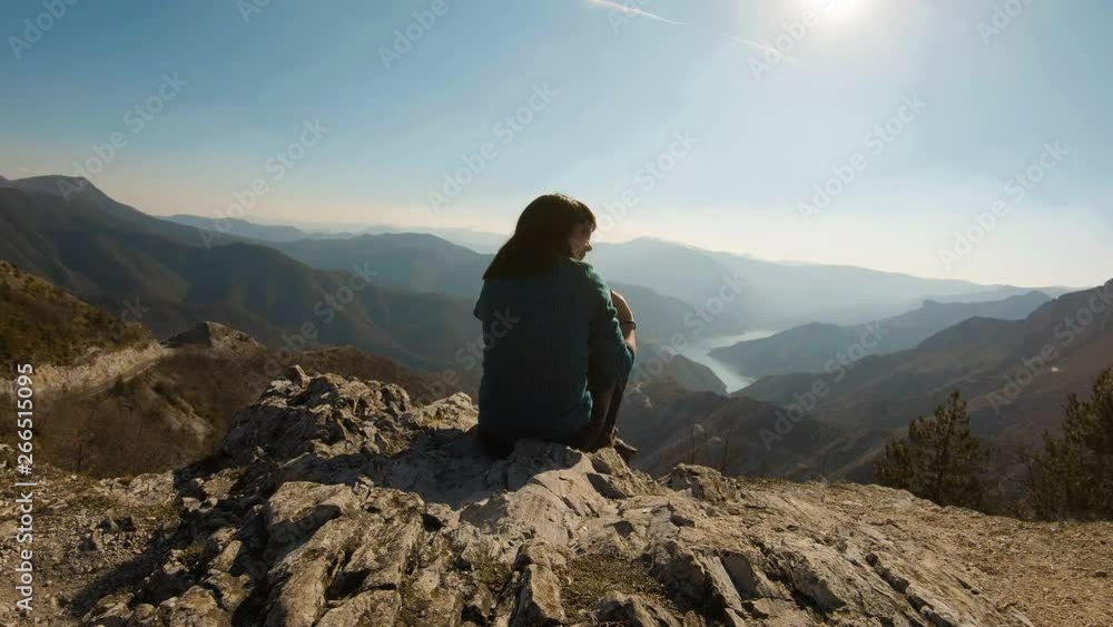 Girl sitting and smiling on a mountain with a beautiful canyon lake in the background