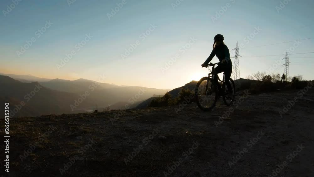 Girl riding her bike at the top of a mountain. Beautiful canyon lake at sunset in the background. Girl riding her bike at the top of a mountain. Beautiful canyon lake at sunset in the background.