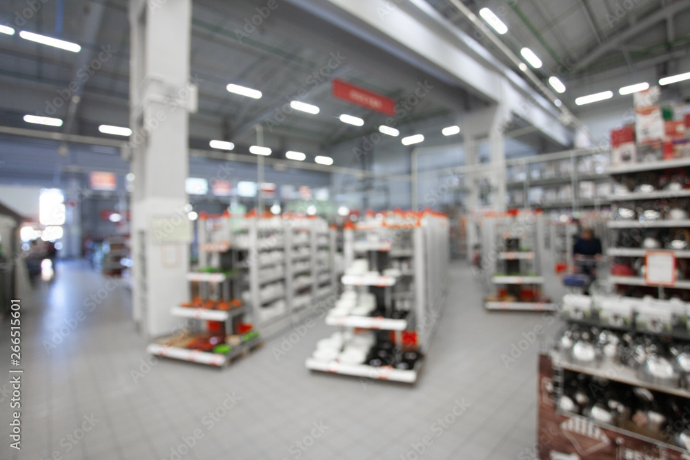 Blurred concept of DIY shopping center. Shelving with household products and kitchenware. Commercial LED lighting. Merchandising in retail.
