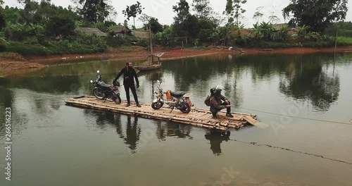 Wallpaper Mural Travel- Couple of bikers crossing the lake on Bamboo raft. the bamboo rafting in the river and natural background. Torontodigital.ca
