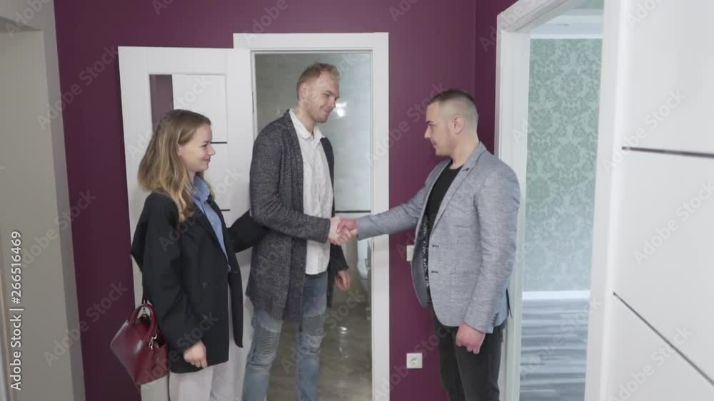Young couple is agreeding with a realtor about a buying a new flat. They are shaking their hands. Young couple is agreeding with a realtor about a buying a new flat. They are shaking their hands.