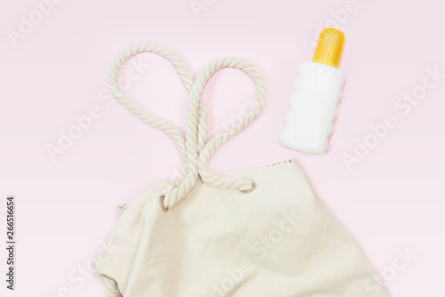 beach bag with beach top view with sunscreen on pink background