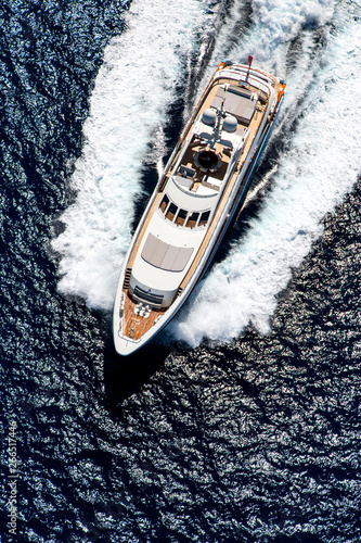 Aerial top view photo of luxury yacht, moving on speed in the open sea with splash and wave © LaptevArt