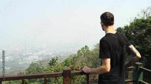 Young man wearing a face mask checking the Chiang Mai cityscape view which is covered with high polluted air. photo