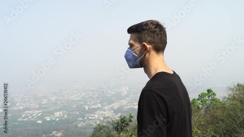 Young Tattooed Man wearing face mask because of Air pollution or virus epidemic in the city.
The pollution is causing poor visibility and smog covered all over the city. photo