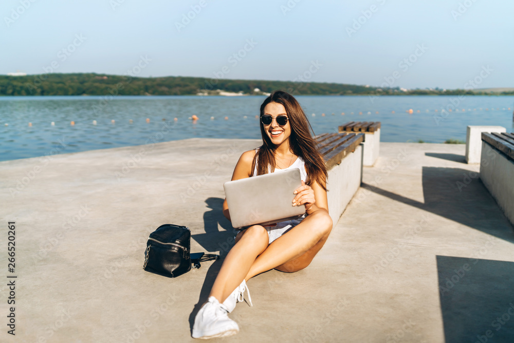 Pretty young girl using laptop outdoor in the city park.