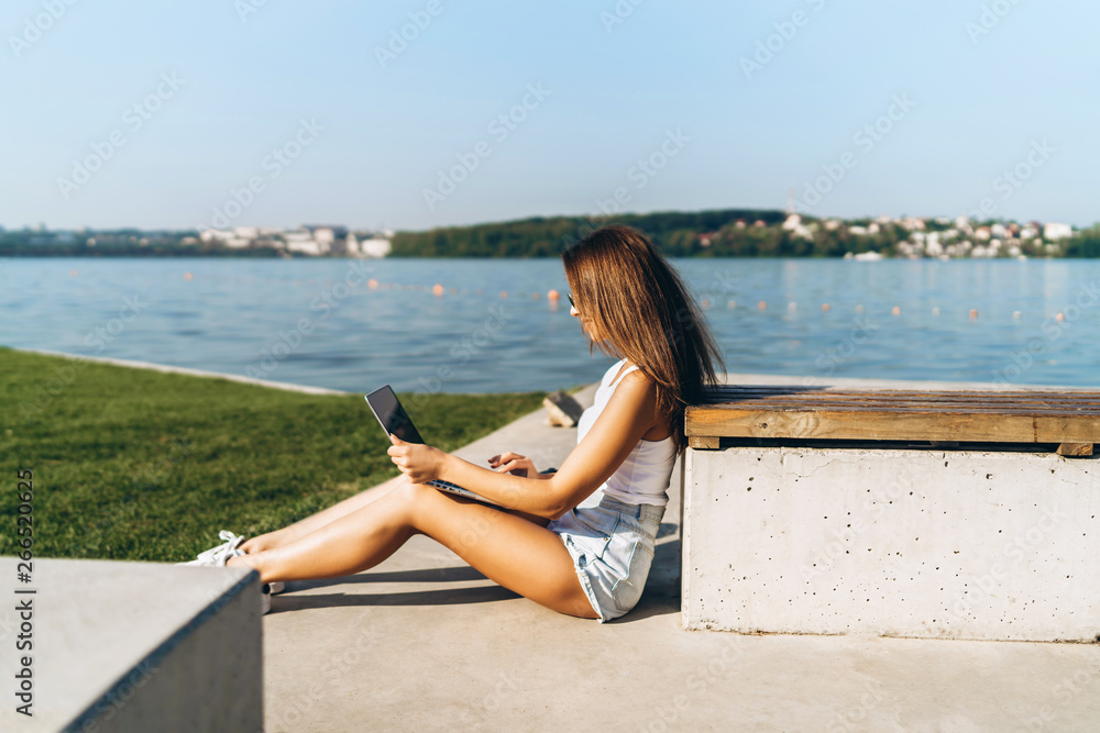 Pretty young girl using laptop outdoor in the city park. Pretty young girl using laptop outdoor in the city park.