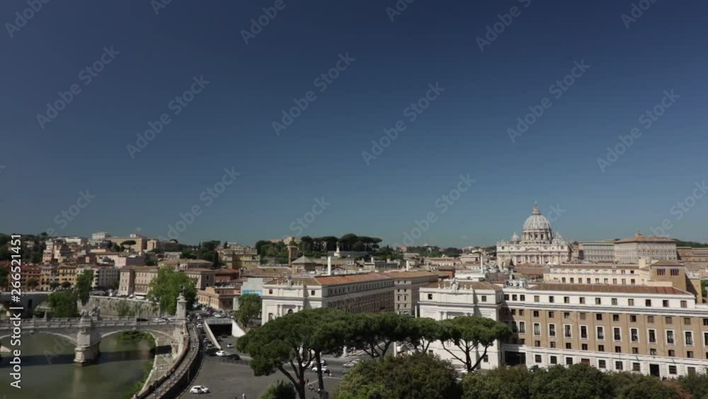 The Vatican and the Vittorio Emanuele Bridge in Rome. Panning from the basilica of San Pietro to the Tiber river in Rome. Blue sky and car traffic. The Vatican and the Vittorio Emanuele Bridge in Rome. Panning from the basilica of San Pietro to the Tiber river in Rome. Blue sky and car traffic.