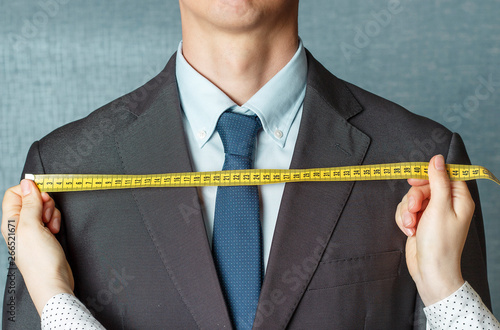Εκτύπωση καμβά The tailor measures the suit with a measuring tape close-up
