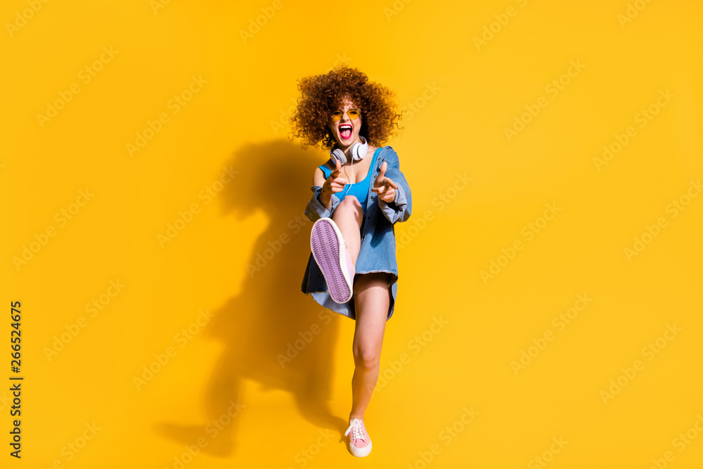 Full length body size photo funky funny she her lady wavy styling clubber strange moves fingers direct wear ear flaps specs casual jeans denim shirt shorts tank top clothes isolated yellow background Full length body size photo funky funny she her lady wavy styling clubber strange moves fingers direct wear ear flaps specs casual jeans denim shirt shorts tank top clothes isolated yellow background