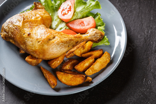 Roasted chicken legs with potato wedges and tomatoes