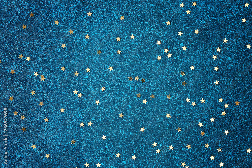 Confetti in the form of gold stars on a blue background. Starry blue ...