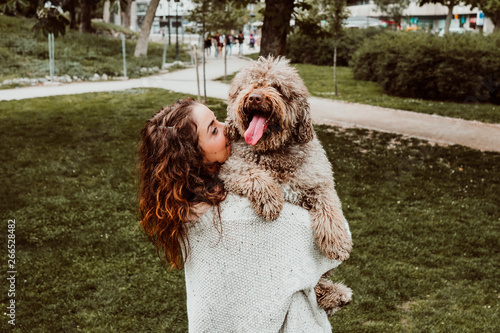.Young and pretty woman spending free time with her nice brown spanish water dog in a park in the center of the city of Madrid. Lifestyle #266528482