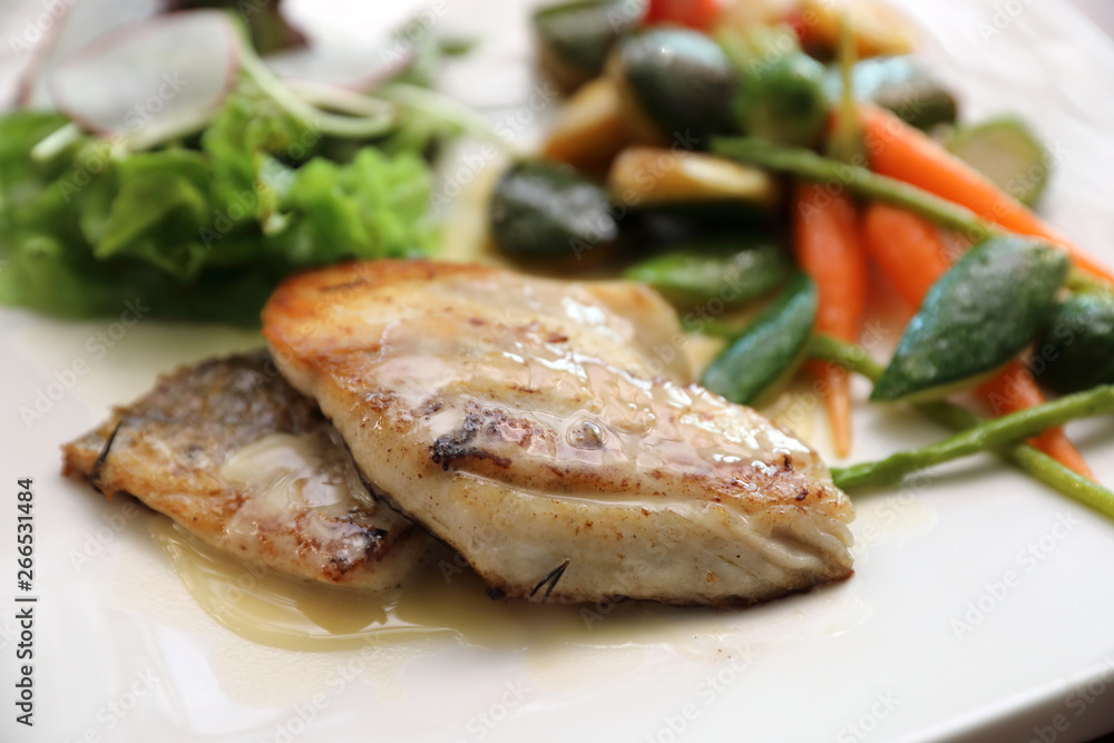 Sea bass fillet with grilled vegetables and salad on wooden table Sea bass fillet with grilled vegetables and salad on wooden table