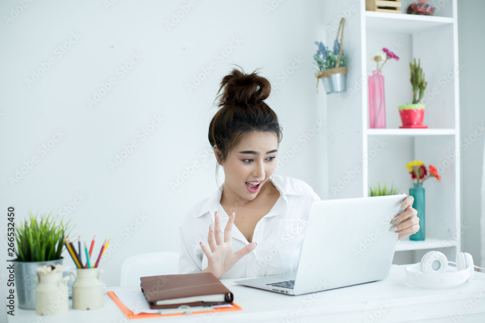 Beautiful young woman working on her laptop in her room.