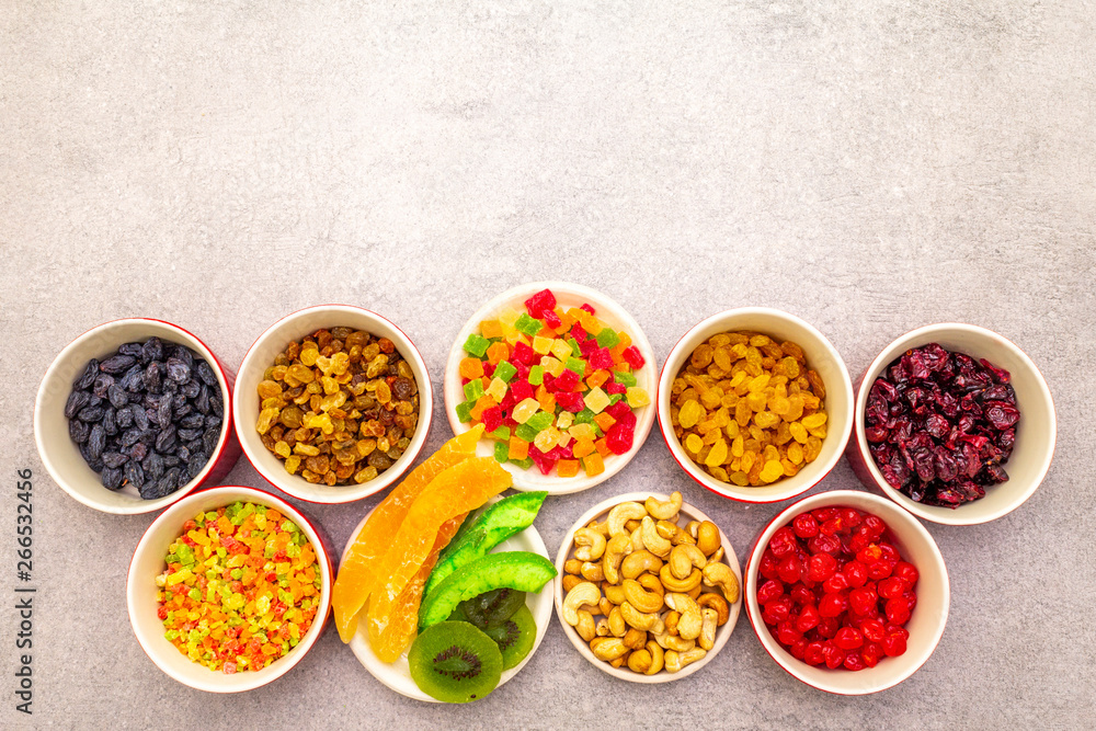 Dried and candied fruit and cashew nuts. Assorted in ceramic bowls on a stone background. Healthy vegetarian (vegan) food concept, copy space, top view. Dried and candied fruit and cashew nuts. Assorted in ceramic bowls on a stone background. Healthy vegetarian (vegan) food concept, copy space, top view.