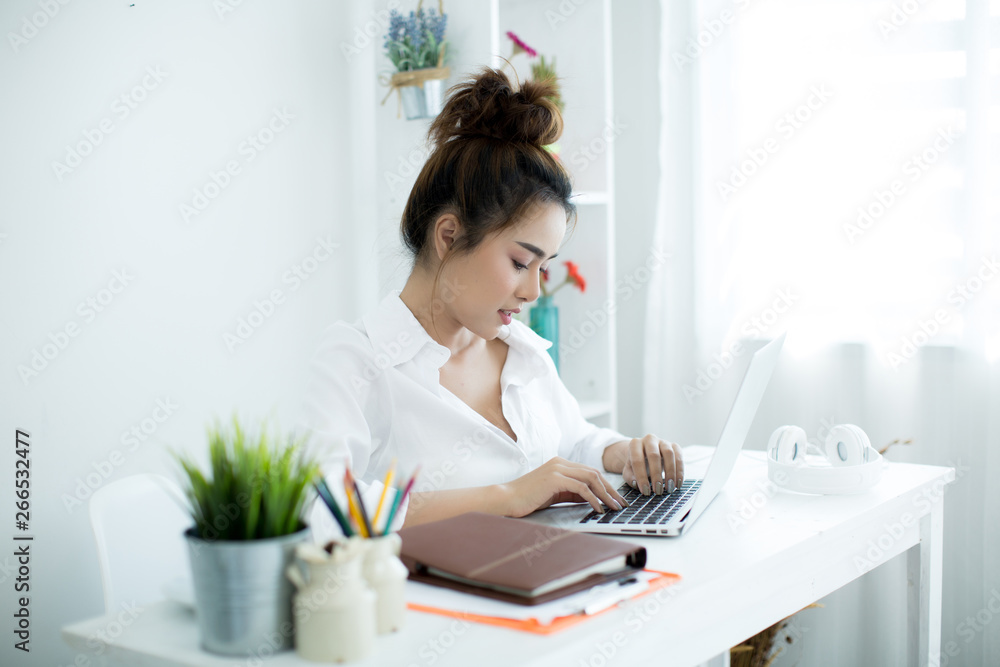 Beautiful young woman working on her laptop in her room. Beautiful young woman working on her laptop in her room.