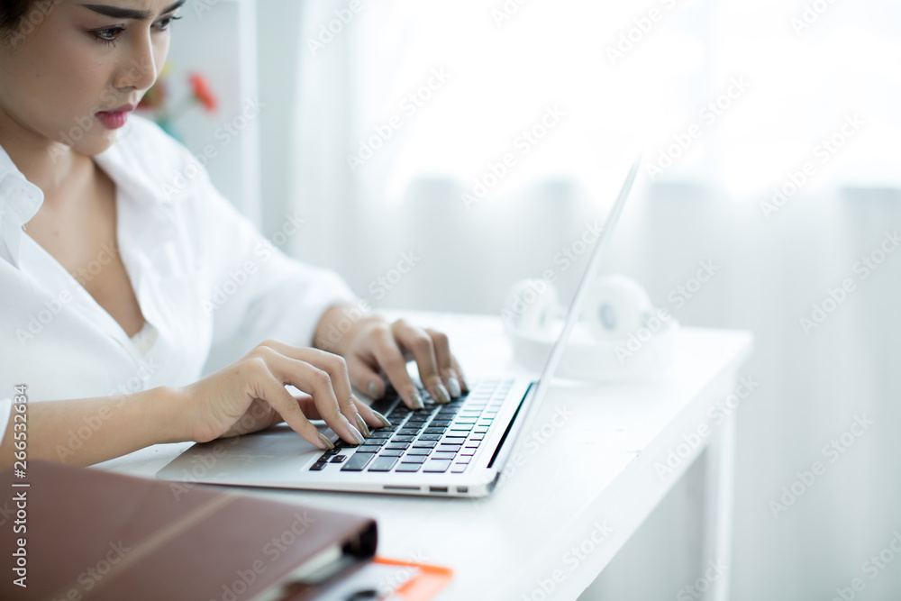 Beautiful young woman working on her laptop in her room. Beautiful young woman working on her laptop in her room.