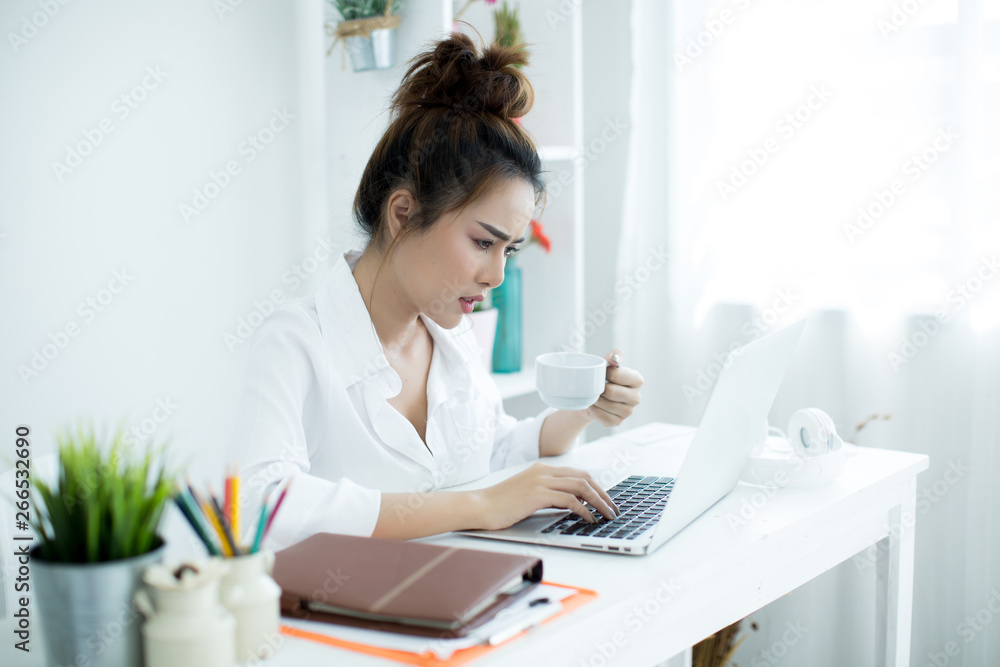 Beautiful young woman working on her laptop in her room. Beautiful young woman working on her laptop in her room.