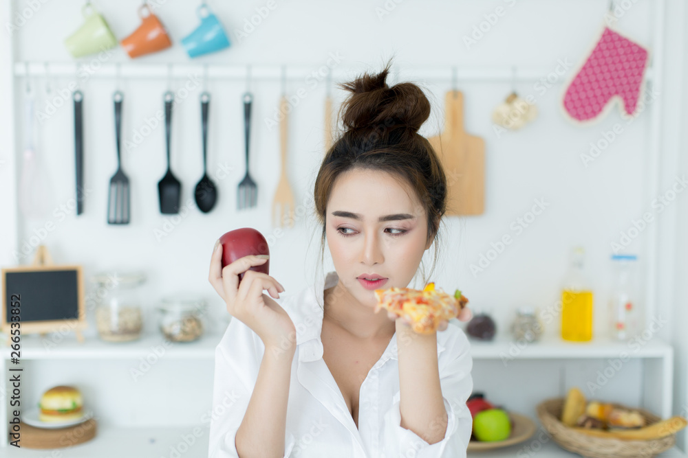 woman choosing between apple and pizza woman choosing between apple and pizza
