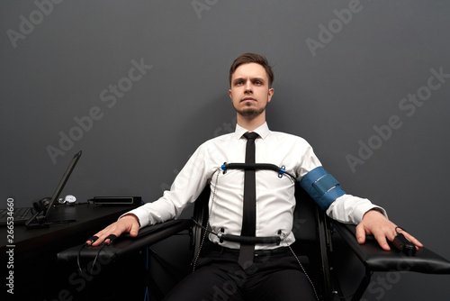 Photos Man sitting with attaching sensors on fingers and  body.