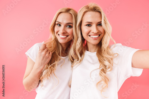 Smiling blonde twins wearing in t-shirts making selfie