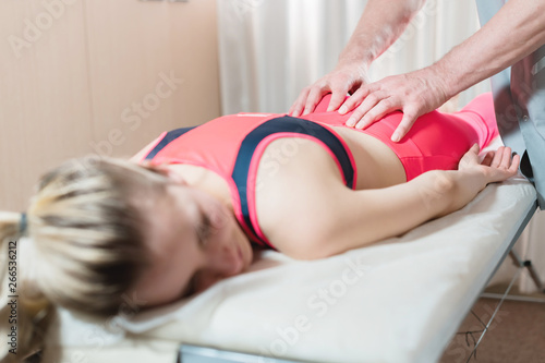 Girl's spine base editing by a male physiotherapist of visceral massage. The hands of the doctor set and knead the tailbone of the patient