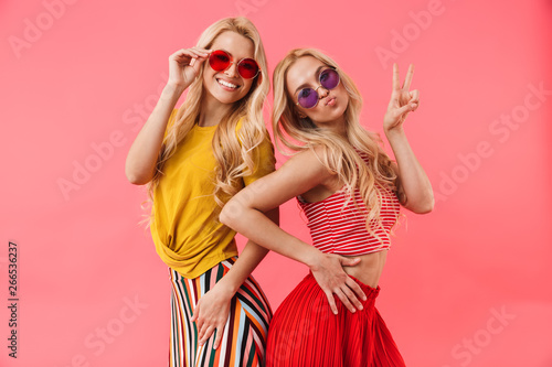 Pleased blonde twins in sunglasses posing together