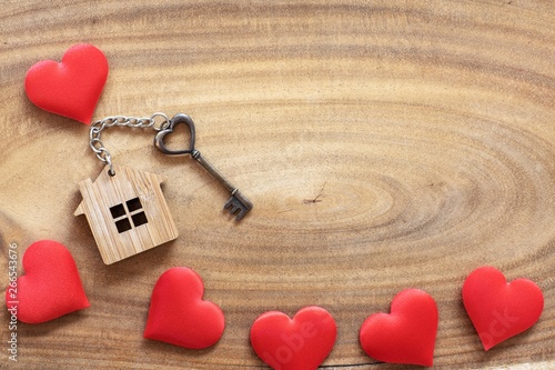 House key in heart shape with home keyring on wood background decorated with mini hearts