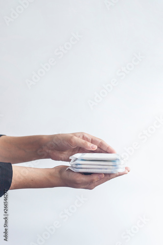 Female's hygiene products. Woman's hand holding a stack of sanitary napkins against white background. Period days concept showing feminine menstrual cycle.