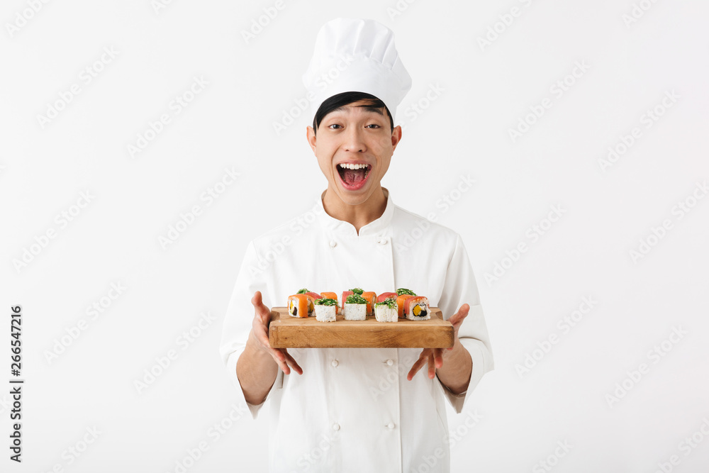 Image of professional chinese chief man in white cook uniform smiling at camera while holding plate with sushi set Image of professional chinese chief man in white cook uniform smiling at camera while holding plate with sushi set