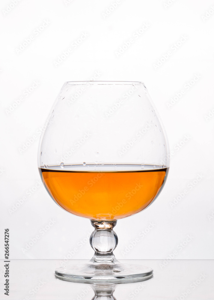 side view of transparent glass on stem with brown drink on white background with copy space side view of transparent glass on stem with brown drink on white background with copy space